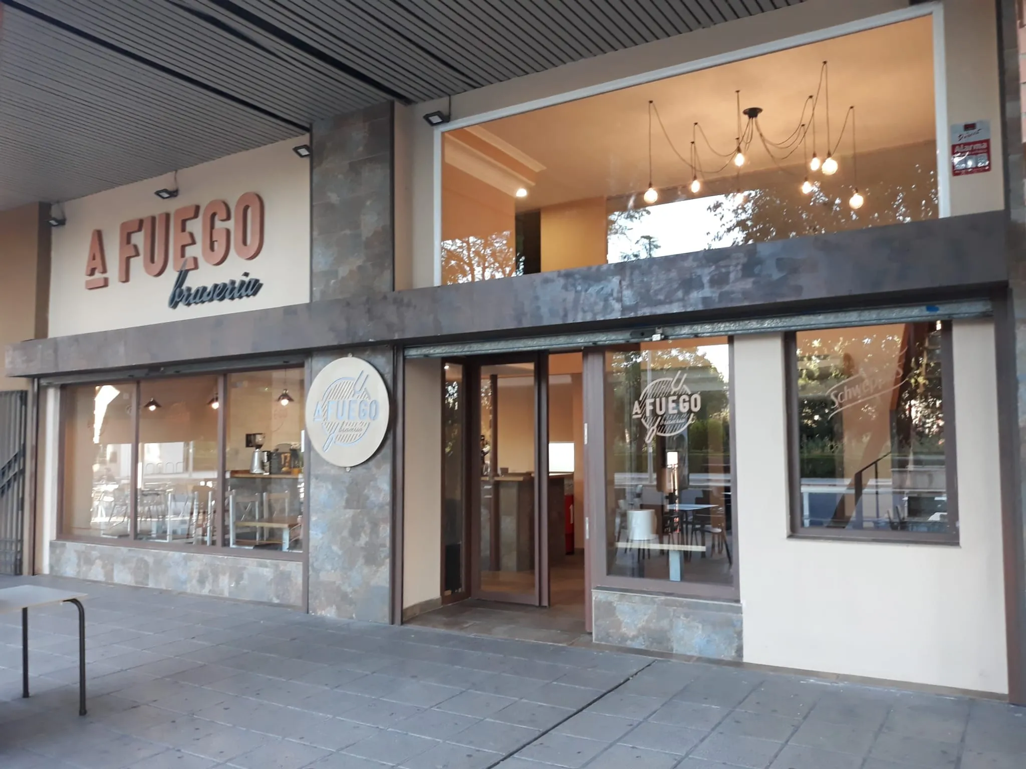 Fachada de A Fuego Brasería en Avenida Al-Nasir, Córdoba, con el rótulo iluminado y la entrada de cristal