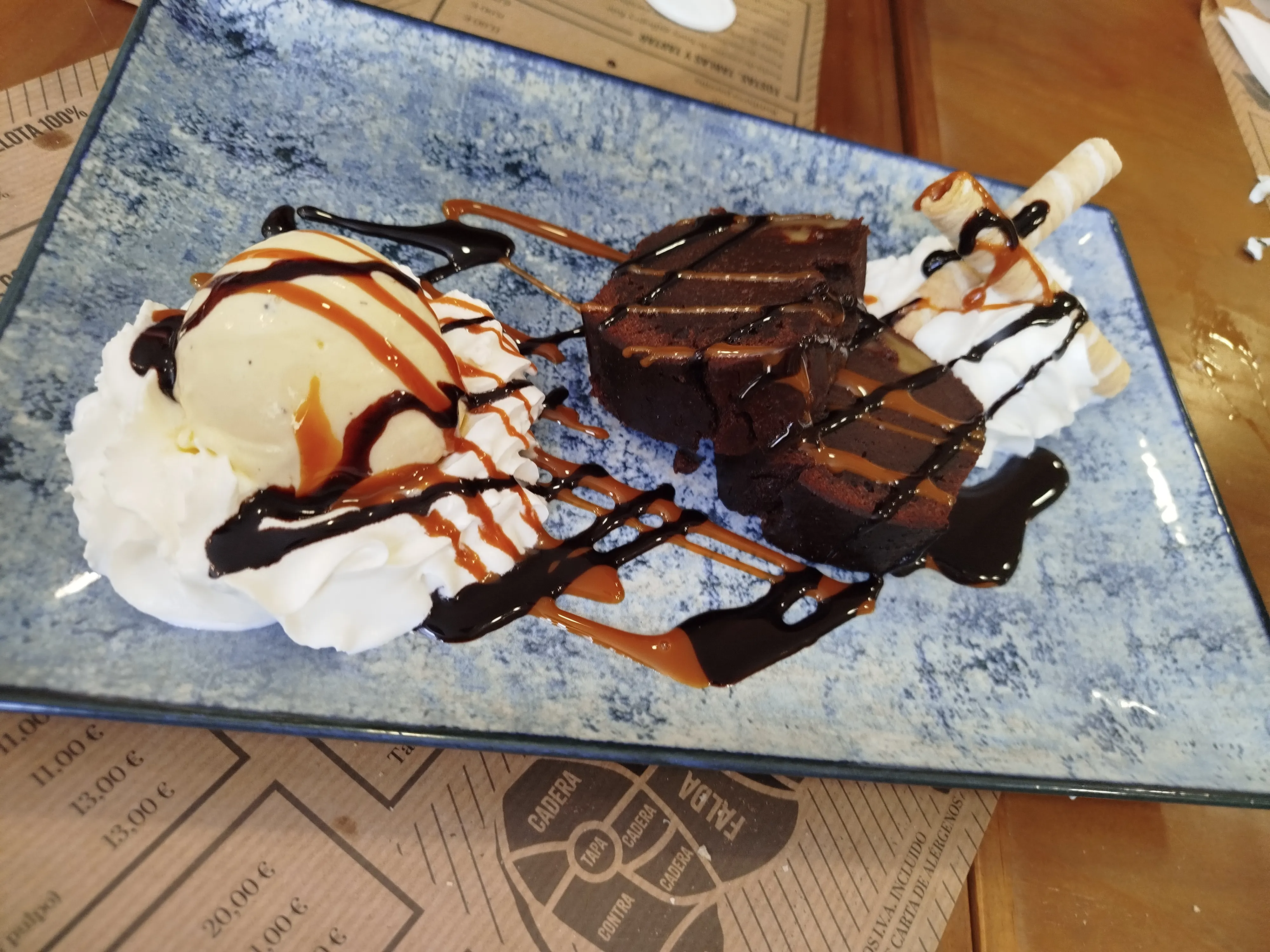 Postre de chocolate con crema, helado y salsa en A Fuego Brasería